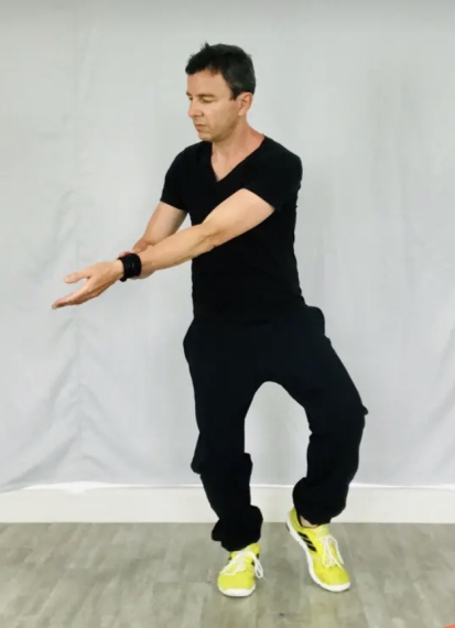 Michael Schrick in einer Qi Gong Bewegung mit gestrektemn arm nahc vorne, offener Handfläche und einer Fußspitze am Boden