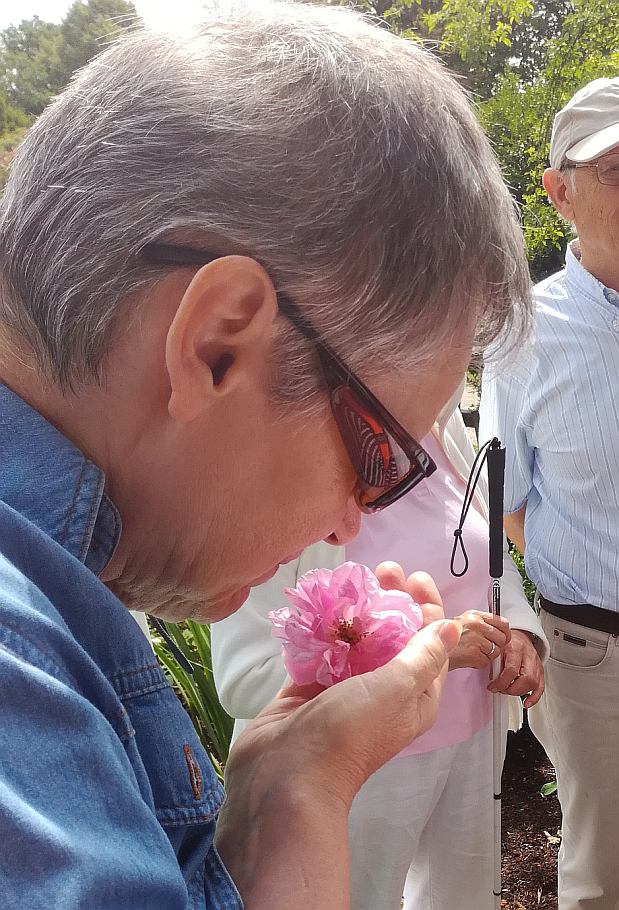 Teilnehmerin schnuppert an einer Rosenblüte in der Hand.