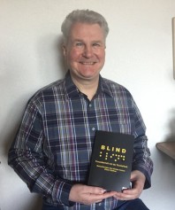Dieter Kleffner hält sitzend sein Buch vor den Bauch, amn sieht das Cover 